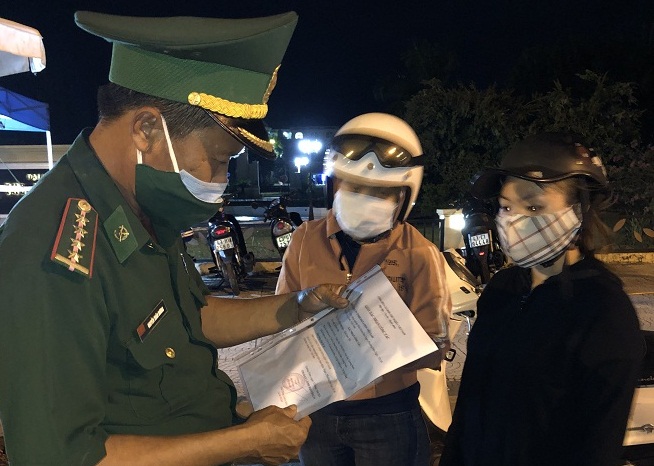 Bộ đội biên phòng tại chốt Trần Đại Nghĩa kiểm tra giấy tờ tùy thân của hai nữ công nhân trước khi cho vào thành phố. Ảnh: N.Đ
