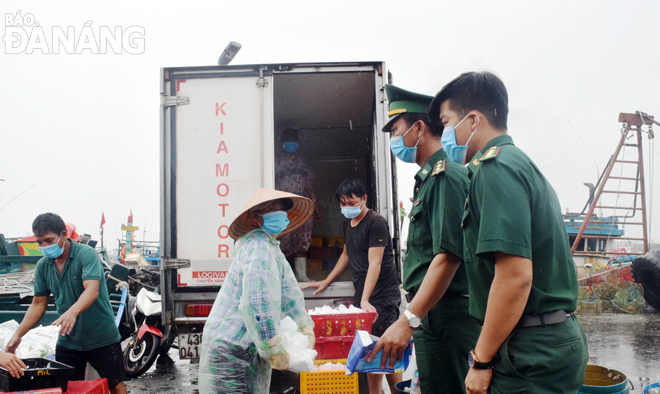 Lực lượng Bộ đội Biên phòng nhắc nhở người dân hoạt động ở cảng cá Thọ Quang tuân thủ nghiêm túc các biện pháp chống dịch.  Ảnh: HOÀNG HIỆP	