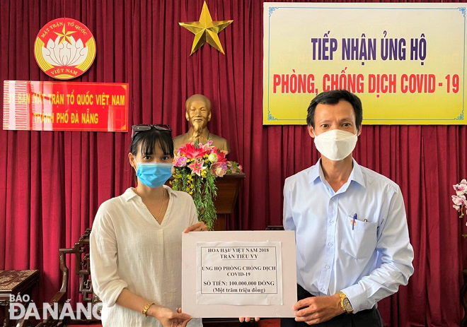 Phó Chủ tịch Ủy ban MTTQ Việt Nam thành phố Lê Văn Minh (phải) tiếp nhận ủng hộ từ Hoa hậu Trần Tiểu Vy (trái). Ảnh: L.P