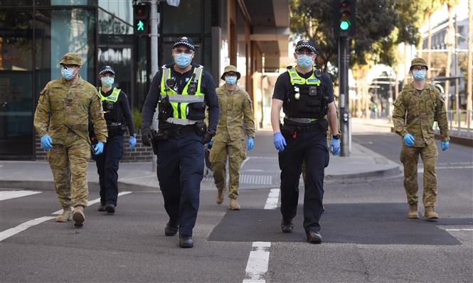 Cảnh sát và binh sĩ tuần tra tại một tuyến phố ở Melbourne, bang Victoria, Australia sau khi chính quyền địa phương áp dụng lệnh hạn chế mới nhằm ngăn chặn sự lây lan của dịch COVID-19, ngày 3/8/2020. Ảnh: AFP/TTXVN