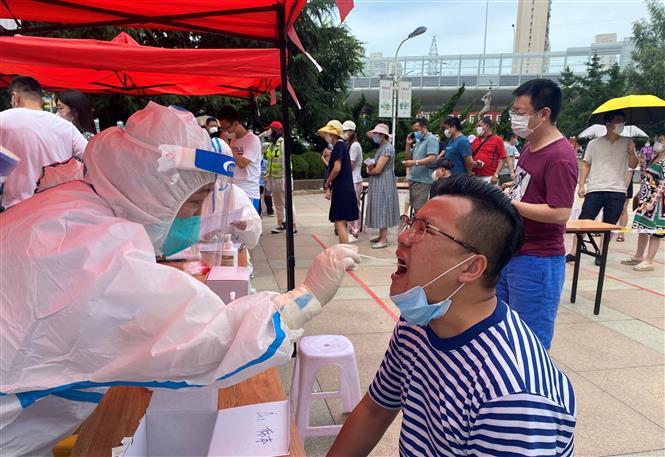 Nhân viên y tế lấy mẫu xét nghiệm COVID-19 tại Đại Liên, tỉnh Liêu Ninh, Trung Quốc. Ảnh: AFP/TTXVN