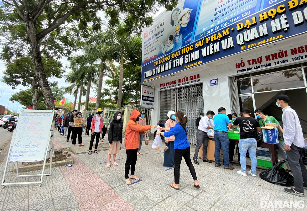 Students lining up two meter apart to wait for their turn to receive food aid