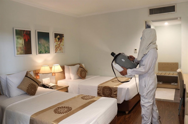 A health worker sprays chemical to disinfect a hotel room in Hà Nội. 