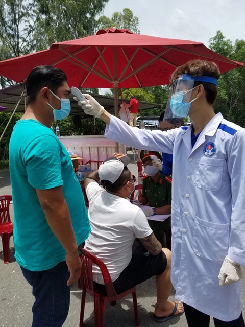 Student Vo Thanh Dong checks people’s temperature