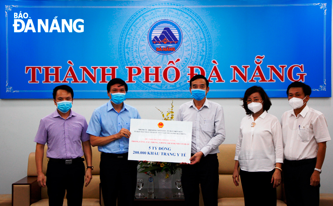 Phó Chủ tịch UBND thành phố Lê Trung Chinh (thứ 3, bên phải) tiếp nhận 5 tỷ đồng và 200.000 khẩu trang y tế từ thành phố Hải Phòng. Ảnh: XUÂN DŨNG	