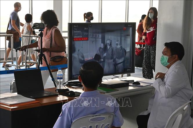 Nhân viên kiểm tra thân nhiệt hành khách bằng máy quét thân nhiệt tại sân bay quốc tế Wattay ở Vientiane, Lào ngày 11/3. Ảnh: AFP/TTXVN