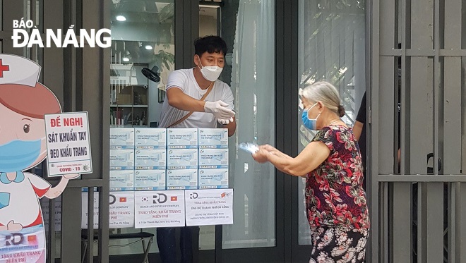 Mr Kim Won Hoon (left) giving free surgical masks to local residents