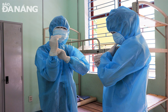 Huy and Oanh puting on their stuffy protective suits to embark on their missions in the centralised quarantine venue.