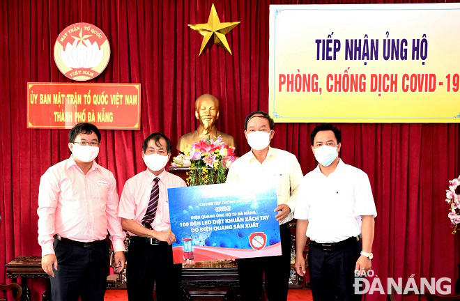 Phó Chủ tịch Ủy ban MTTQ Việt Nam thành phố Dương Đình Liễu (thứ 2, phải sang) tiếp nhận hỗ trợ từ đại diện Công ty CP Bóng Đèn Điện Quang. Ảnh: L.P