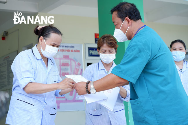 Doctor Le Thanh Phuc, the Director of Da Nang Lung Hospital, is seen handing over the discharge papers to the patients who have been cleared of the novel coronavirus