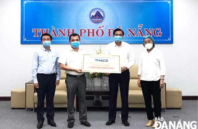Đại diện Công ty CP ô-tô Trường Hải trao tặng biển tượng trưng trị giá 5 tỷ đồng cho Phó Chủ tịch UBND thành phố Trần Văn Miên (thứ hai, phải sang). Ảnh: T.L