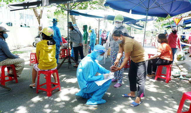 Nhân viên y tế lấy thông tin các tiểu thương kinh doanh tại chợ Nại Hiên Đông để lấy mẫu xét nghiệm. Ảnh: PHAN CHUNG