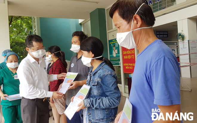 Phó Bí thư Thường trực Thành ủy Nguyễn Văn Quảng (trái) hỏi thăm sức khỏe và trao giấy ra viện cho các bệnh nhân nhiễm Covid-19 đã được điều trị khỏi sáng 14-8 tại Bệnh viện dã chiến Hòa Vang. Ảnh: PHAN CHUNG	