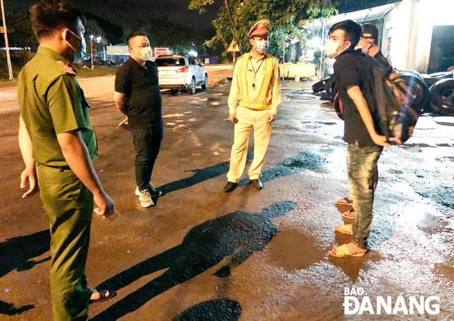 Tối 15-8, lực lượng Cảnh sát giao thông, Trạm Cảnh sát giao thông cửa ô Hòa Nhơn đã bàn giao 2 thanh niên chờ đón xe khách cho Công an xã Hòa Sơn xử lý theo quy định phòng, chống Covid-19.  Ảnh: NGỌC ĐOAN	
