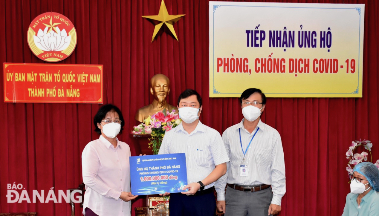 Authorized by VNPT, Chief Representative of the VNPT Da Nang Vu Truong Giang (centre) handing one billion VND in cash donations to a representative from the Da Nang Fatherland Front Committee