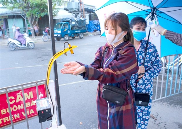 A woman uses Weekend Club's touchless hand santiliser dispenser at Khanh Hoa market, Da Nang  (Photo: VNA)