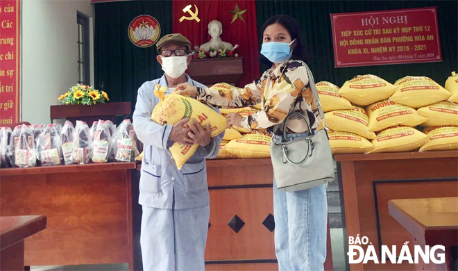 Đại diện một doanh nghiệp (phải) tặng quà cho người dân nghèo ở phường Hòa An (quận Cẩm Lệ).                Ảnh: T.S