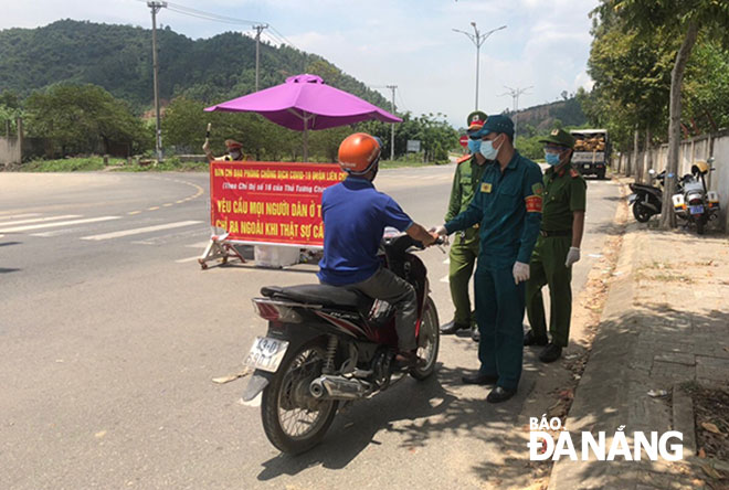 Dân quân tự vệ Đào Văn Tuấn (thứ 2, phải sang) làm nhiệm vụ tại chốt kiểm soát dịch trên tuyến đường Hoàng Văn Thái, quận Liên Chiểu. Ảnh: P.C	