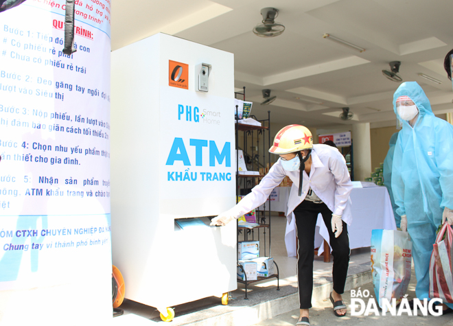 A woman receiving face masks from a ‘face mask ATM’ installed at the supermarket