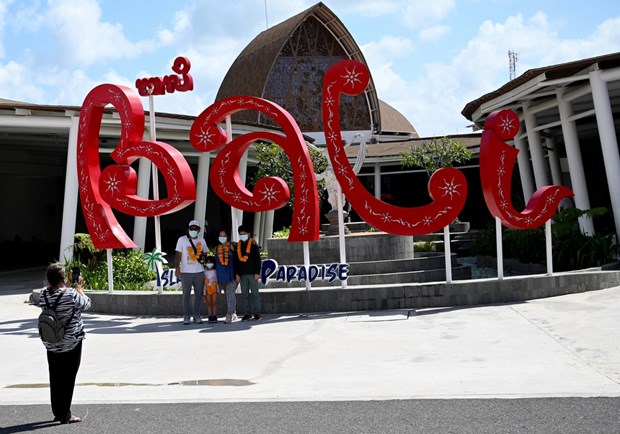 Tourists have their picture taken at Ngurah Rai International Airport in Bali on July 31 (Photo: AFP)