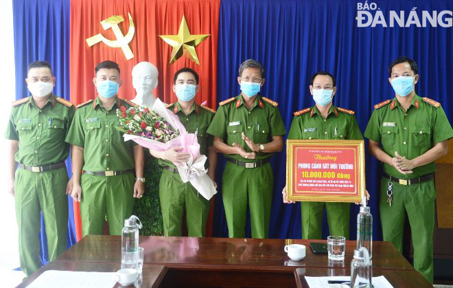 Lãnh đạo Công an thành phố Đà Nẵng (thứ 4 từ trái qua) trao tiền của UBND thành phố thưởng nóng cho Phòng Cảnh sát môi trường. Ảnh: HOÀNG HIỆP