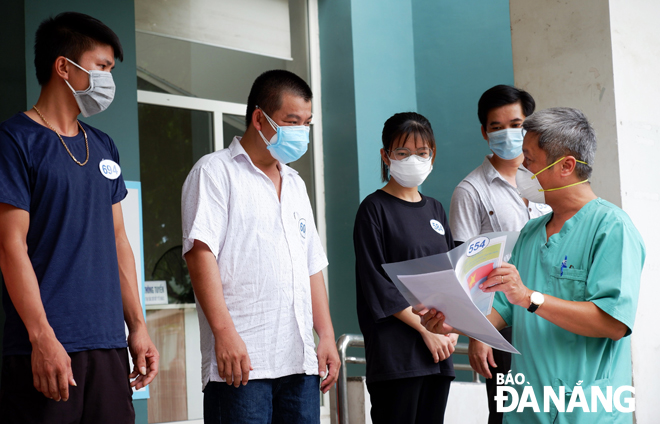 Thứ trưởng Bộ Y tế Nguyễn Trường Sơn (bìa phải) thăm hỏi và trao giấy ra viện cho các bệnh nhân Covid-19 được điều trị khỏi tại Bệnh viện dã chiến Hòa Vang ngày 18-8. 					Ảnh: PHAN CHUNG