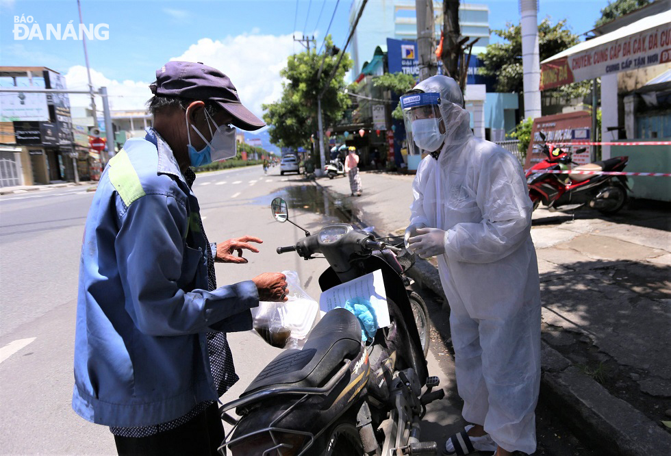 Mr Nguyen Duy Duc (right) giving a free portion of rice to 57-year-old Le Van Ba, a sanitation worker.