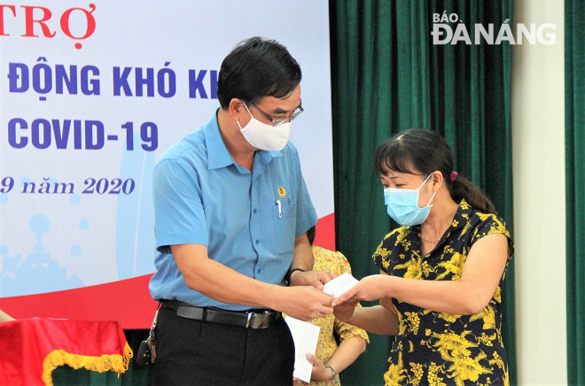 Vice Chairman of the municipal Labour Union Hoang Huu Nghi (left) presenting cash gifts to poor members