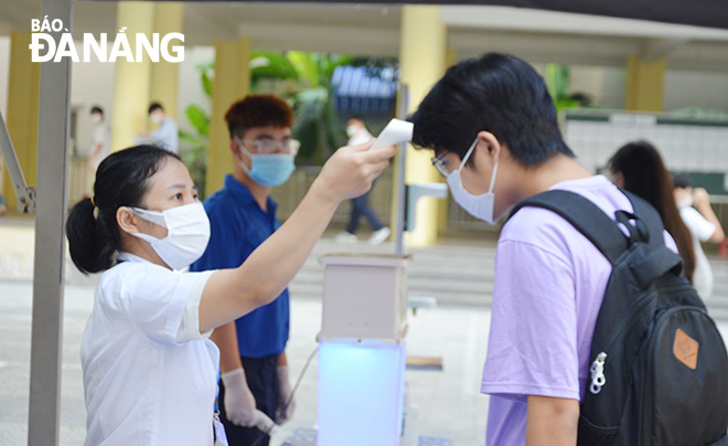 Cán bộ y tế đo thân nhiệt cho thí sinh tại điểm thi Trường THPT Trần Phú. Ảnh: NGỌC PHÚ