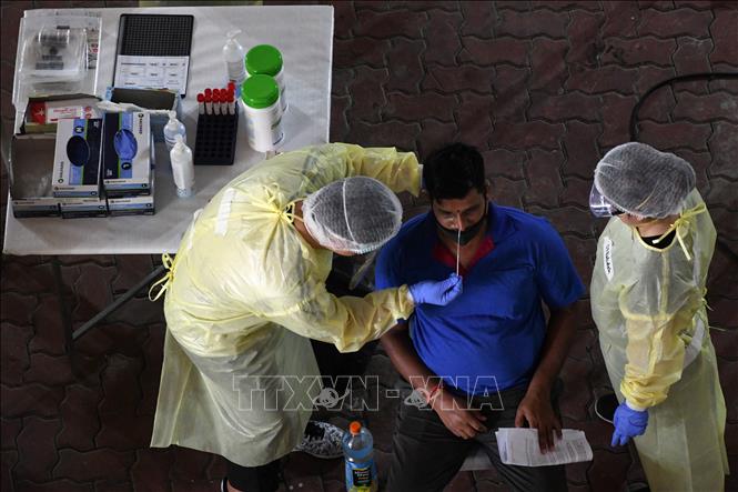 Nhân viên y tế lấy mẫu dịch xét nghiệm COVID-19 cho người lao động tại Singapore ngày 10/6. Ảnh: AFP/TTXVN