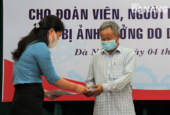 Chairwoman of the municipal Trade Union Nguyen Thi Dung (left) presenting cash gifts to poor members