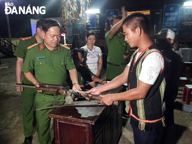 Trung tá Lê Văn Tư (bìa trái), Trưởng Công an xã Hòa Bắc tiếp nhận vũ khí, công cụ hỗ trợ do người dân giao nộp. (Ảnh chụp giữa tháng 4-2020)Ảnh: PHƯƠNG CHI