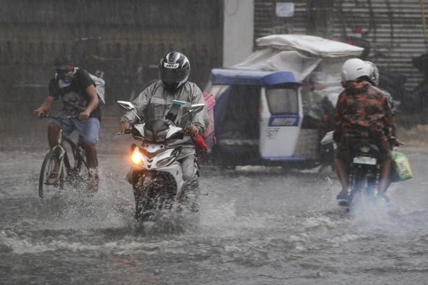 People wearing face masks cross a flooded street during a brief downpour in Quezon city, Philippines Sept. 7, 2020 (Photo: AP)