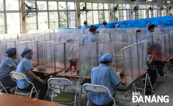 Workers of the Daiwa Vietnam Co., Ltd., eating their lunch on desks with plastic partitions