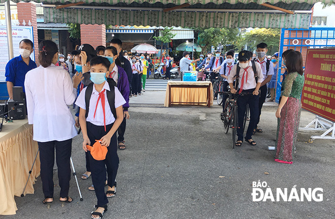 Luong The Vinh Junior High pupils lining up for temperature checks