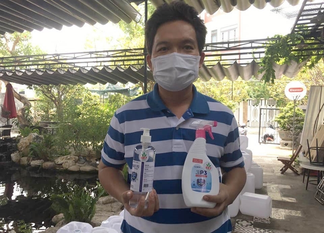 Mai Anh Duc in Da Nang holds bottles of antiseptic solution