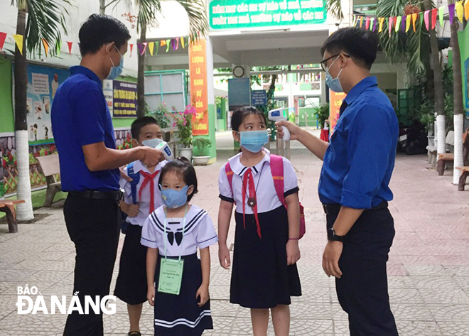 Đoàn Thanh niên Trường tiểu học Điện Biên Phủ (quận Thanh Khê) đo thân nhiệt cho học sinh trước khi các em vào lớp học buổi đầu tiên.