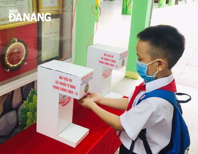 A pupil of the Dien Bien Phu Primary School washing his hands with an automatic hand sanitiser dispenser 