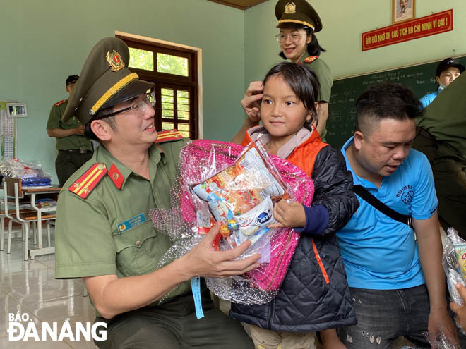 A representative from the Division of the Party and Political Affairs presenting gifts to poor pupils in Quang Nam Province’s Nam Tra My District