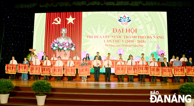 Bí thư Thành ủy Trương Quang Nghĩa và Chủ tịch UBND thành phố Huỳnh Đức Thơ (giữa) tặng Cờ thi đua cho các tập thể xuất sắc thuộc khối, cụm thi đua tại Đại hội. Ảnh: ĐẶNG NỞ	