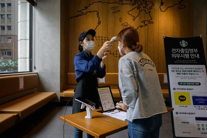 Kiểm tra thân nhiệt phòng lây nhiễm COVID-19 tại một quán cà phê ở Seoul, Hàn Quốc, ngày 31/8/2020. Ảnh: AFP/ TTXVN