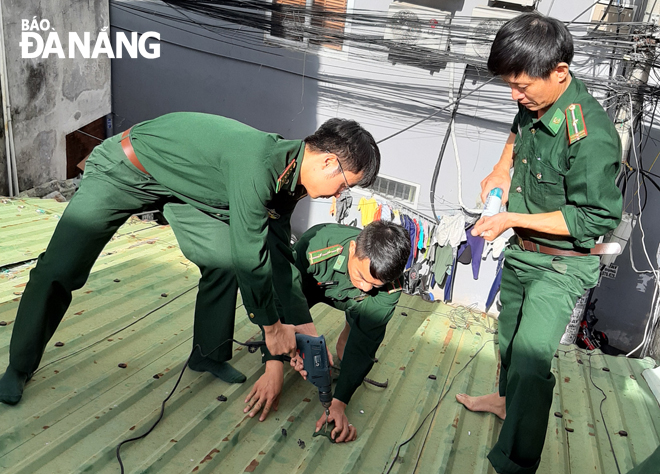 Cán bộ, chiến sĩ Biên phòng Cửa khẩu Cảng Đà Nẵng giúp dân sửa chữa nhà trước mùa mưa bão năm 2020.Ảnh: KIM NGÂN	