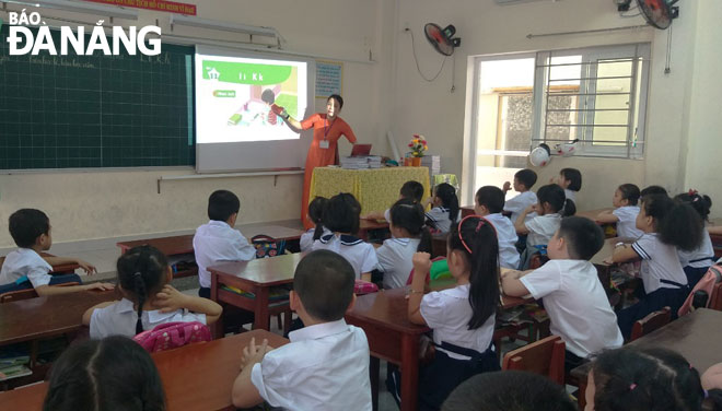 Cô Phan Thị Hồng Trang, giáo viên chủ nhiệm lớp 1/2 Trường tiểu học Lê Lai dạy đánh vần kết hợp bổ trợ hình ảnh bằng máy chiếu để tạo hứng khởi cho học sinh khi học. Ảnh: NGỌC PHÚ	