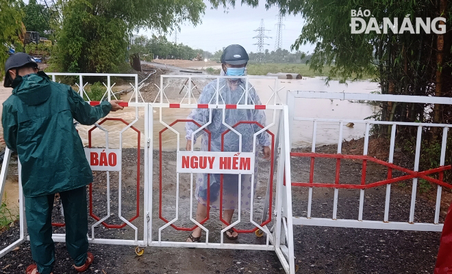 Lực lượng chức năng xã Hòa Liên rào chắn đường công vụ qua công trình cầu Quảng vì lũ tràn qua, bảo đảm an toàn cho người dân. Ảnh: HOÀNG HIỆP