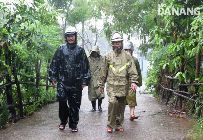 Phó Bí thư Thường trực Thành ủy Nguyễn Văn Quảng (bìa phải) theo người dân thôn Tây An, xã Hòa Châu vào khu vực ngập lũ. Ảnh: HOÀNG HIỆP