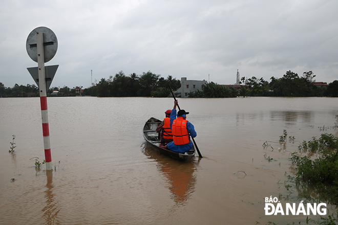 People ride on boat in a flooded area in Hoa Khuong Commune