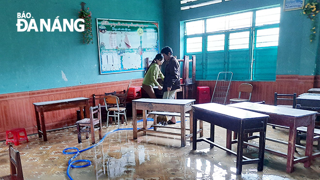 Giáo viên Trường tiểu học Hòa Liên (điểm trường Trường Định) dọn dẹp vệ sinh trường, lớp sau khi nước rút ra bên ngoài sân. 