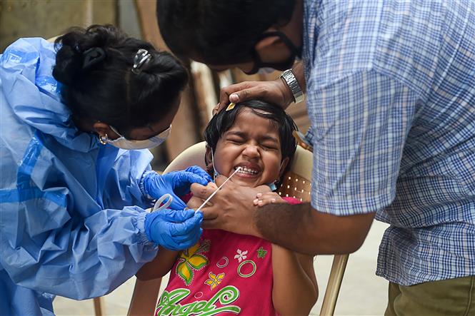 Nhân viên y tế lấy mẫu dịch xét nghiệm COVID-19 cho trẻ em tại Mumbai, Ấn Độ, ngày 3/10/2020. Ảnh: AFP/ TTXVN