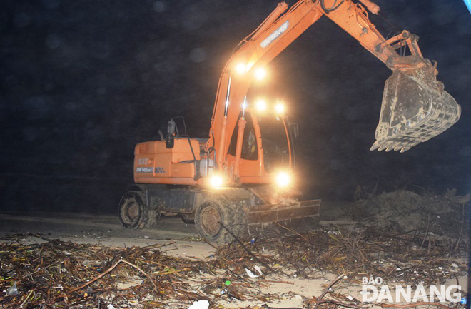 Các đơn vị chức năng tranh thủ thu dọn rác bãi biển vào ban đêm nhanh chóng khắc phục hậu quả của áp thấp nhiệt đới. Trong ảnh: Dùng phương tiện cơ giới thu dọn rác tấp vào bãi biển Mỹ Khê vào tối 16-10. Ảnh: HOÀNG HIỆP