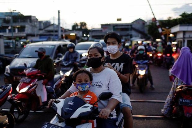 Mask-wearers waiting to cross a railway line in Indonesia which now has the highest number of coronavirus cases in Southeast Asia. (Photo: Reuters)